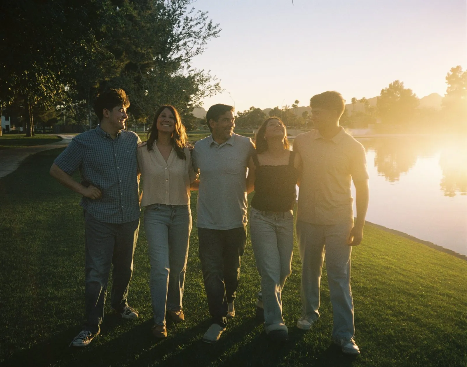 Family walking arm in arm by a lake at sunset, shot on 35mm film