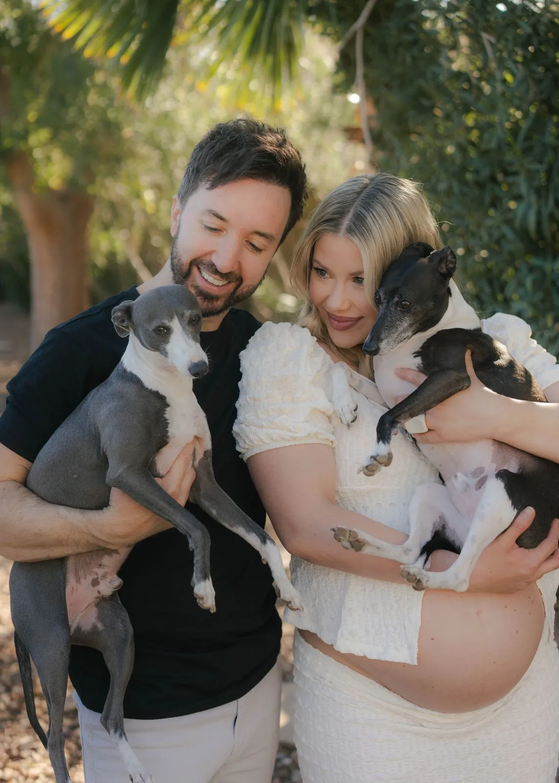 Expecting couple laughing with their two dogs