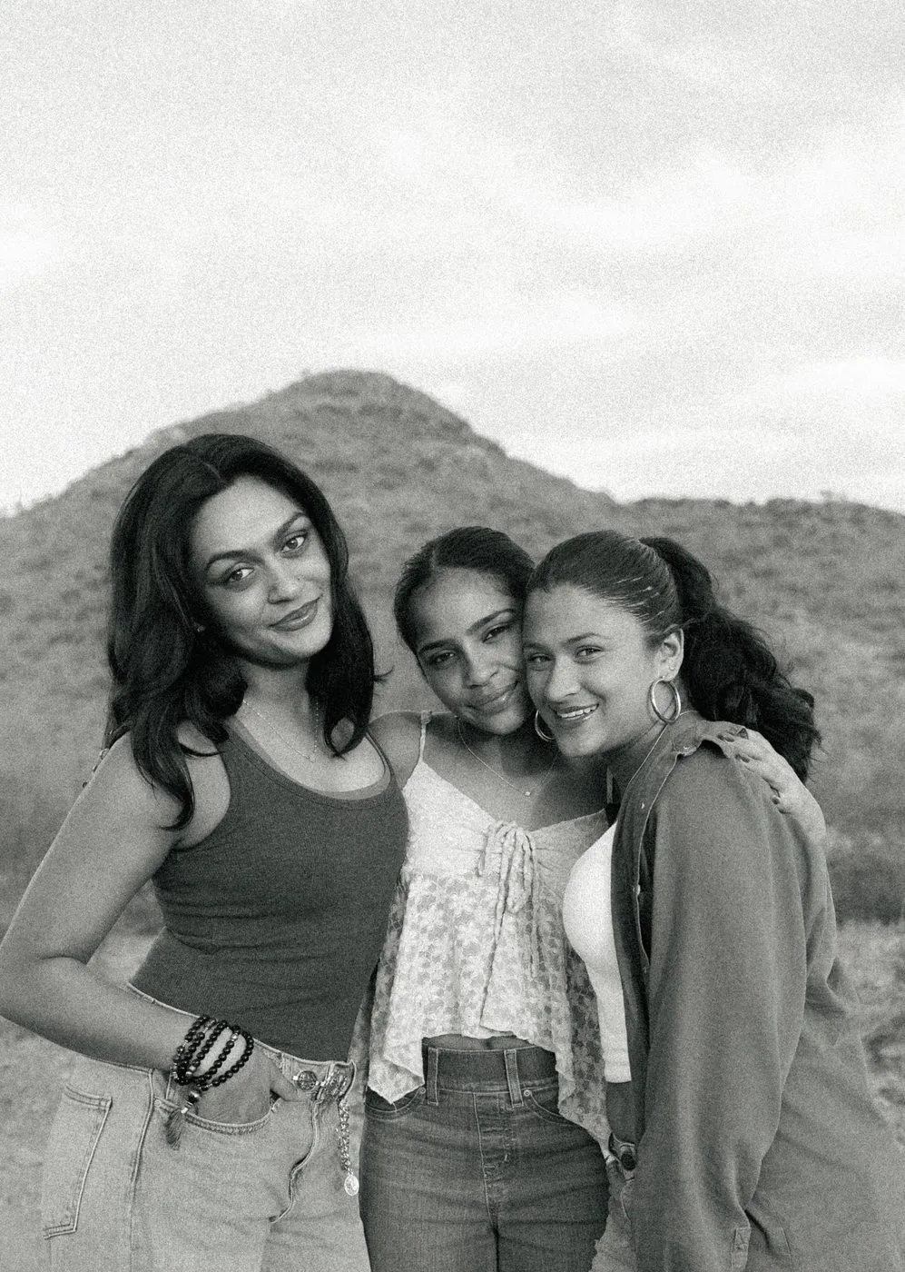 Three sisters cuddled up in the desert, in black and white