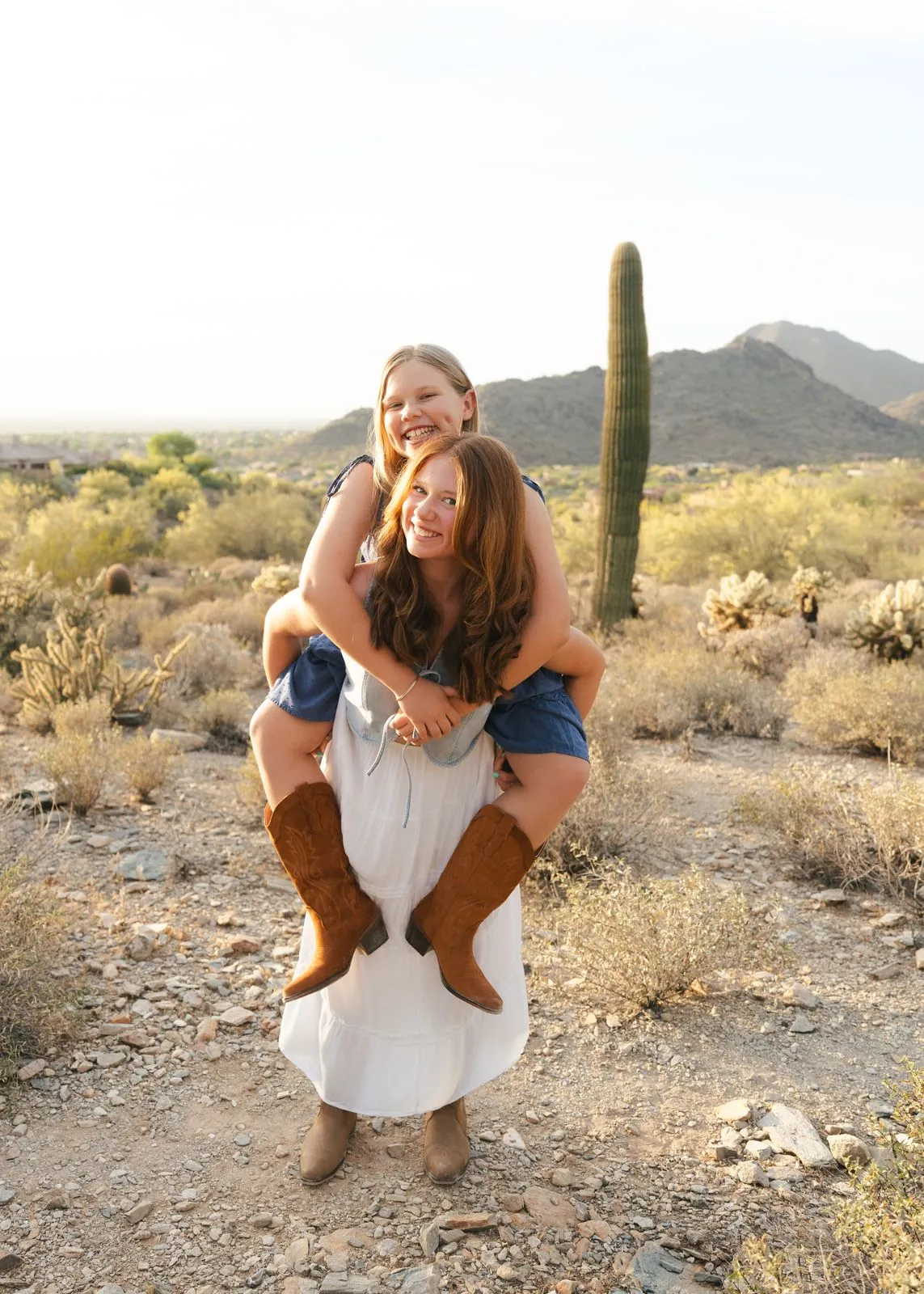 Sisters laughing during a piggyback in the desert