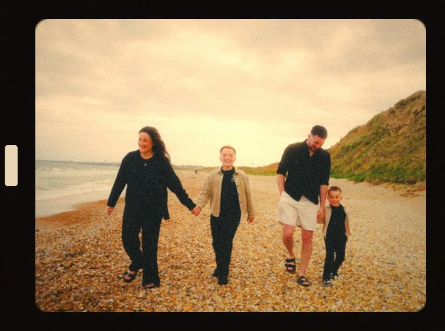 Family walking hand in hand on the beach, framed like a Super 8 film still