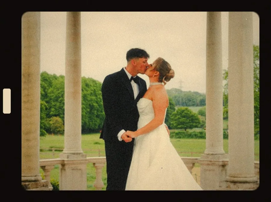 Couple kissing between stone columns, framed like a Super 8 film still