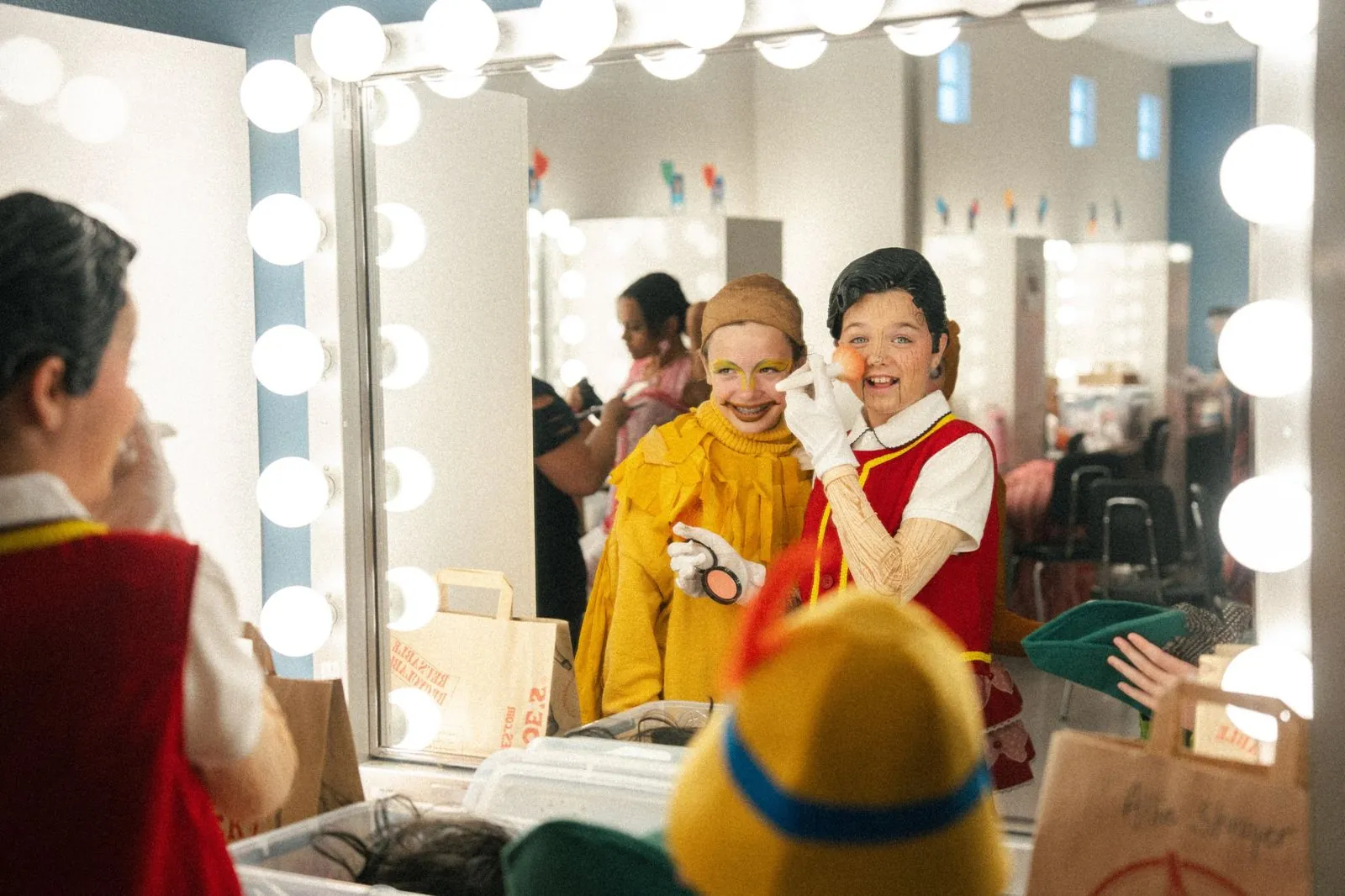 Young actors doing their make-up in a dressing room mirror